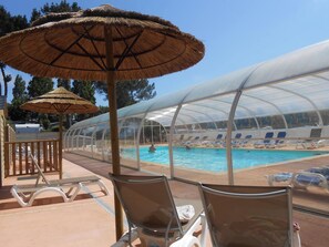 A pool area with lounge chairs and umbrellas, a covered seating area, and a transparent greenhouse structure. - New Listing (Binic-Étables-sur-Mer)