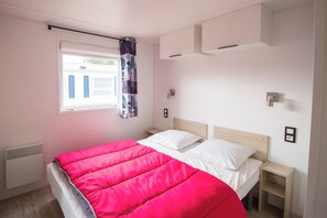 A bedroom with a bed, a window with curtains, a wall-mounted air conditioning unit, and bedside tables. - New Listing (Binic-Étables-sur-Mer)