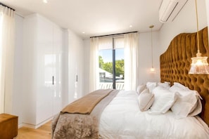 A bedroom with a large bed, a wardrobe, and a view through a glass door. - Penthouse at Aan de Meul (Stellenbosch)