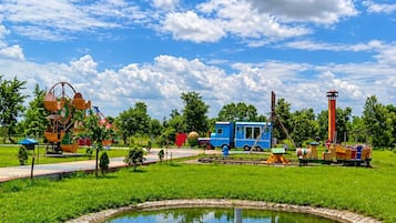 A park with a pond, playground, and a blue train.