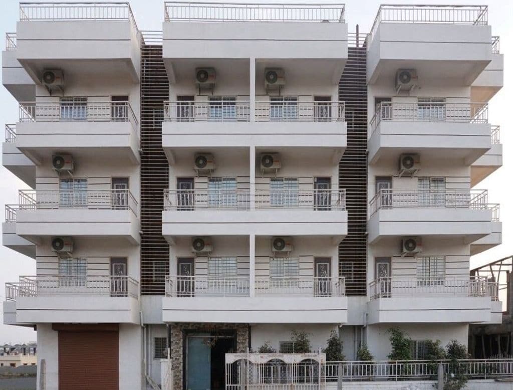 Um edifício residencial com várias andares, varandas, aparelhos de ar condicionado e uma escadaria.
