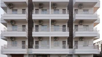 Um edifício residencial com várias andares, varandas, aparelhos de ar condicionado e uma escadaria.