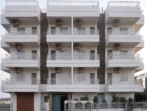 Un edificio residencial de varios pisos con balcones, unidades de aire acondicionado y una escalera.