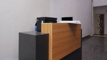 Um balcão de recepção com base preta e painel de madeira, uma impressora preta e um laptop preto em cima.