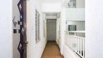 A narrow hallway with a wooden floor, white walls, and a door with a geometric design.