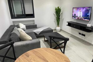 A modern living room with a grey sofa, a wooden coffee table, and a television mounted on the wall. - Stylish Living at Kacem Palace (Tunis Governorate)