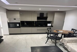 A compact kitchen with modern appliances, a dining area with a round table and chairs, and a sofa. - Stylish Living at Kacem Palace (Tunis Governorate)
