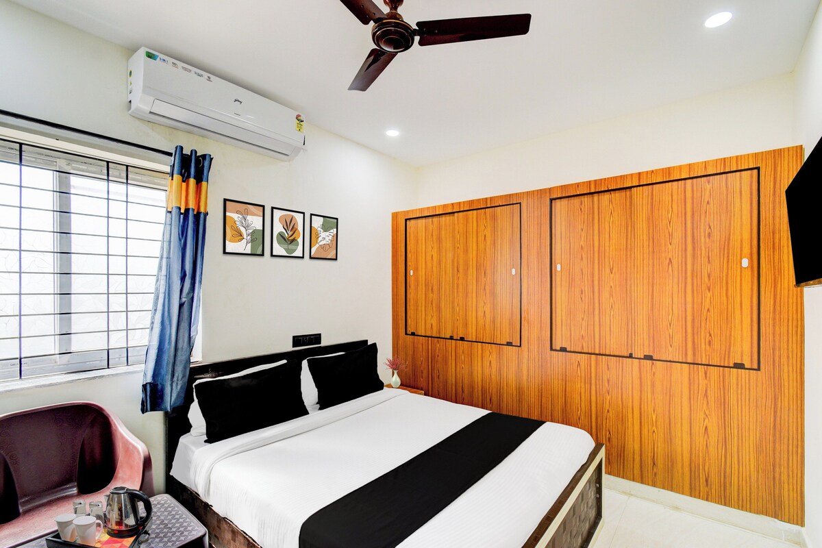 Habitación de hotel con una cama, un escritorio con silla, un ventilador de techo y una ventana con cortinas.