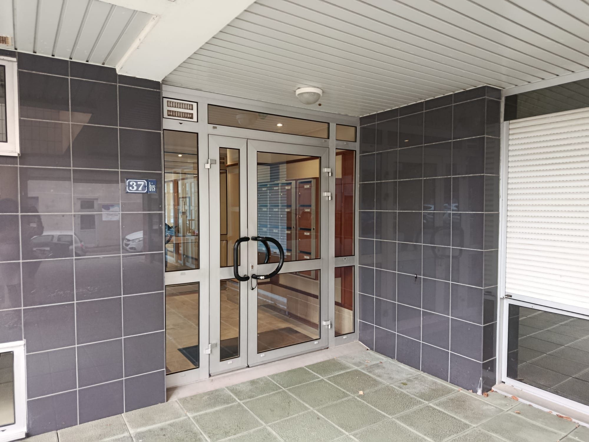 A hotel entrance with a glass door, a visible number '37', and a tiled floor.