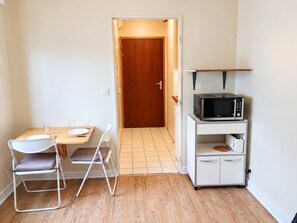 Cocina compacta con una mesa de comedor, sillas, microondas y un mueble pequeño.