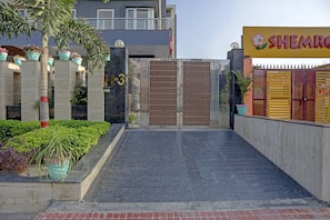 A gated entrance to a property with a modern design, featuring a metal gate and a concrete pathway leading to a building with a balcony. - Townhouse Merriment Near ISKCON Temple (Noida)