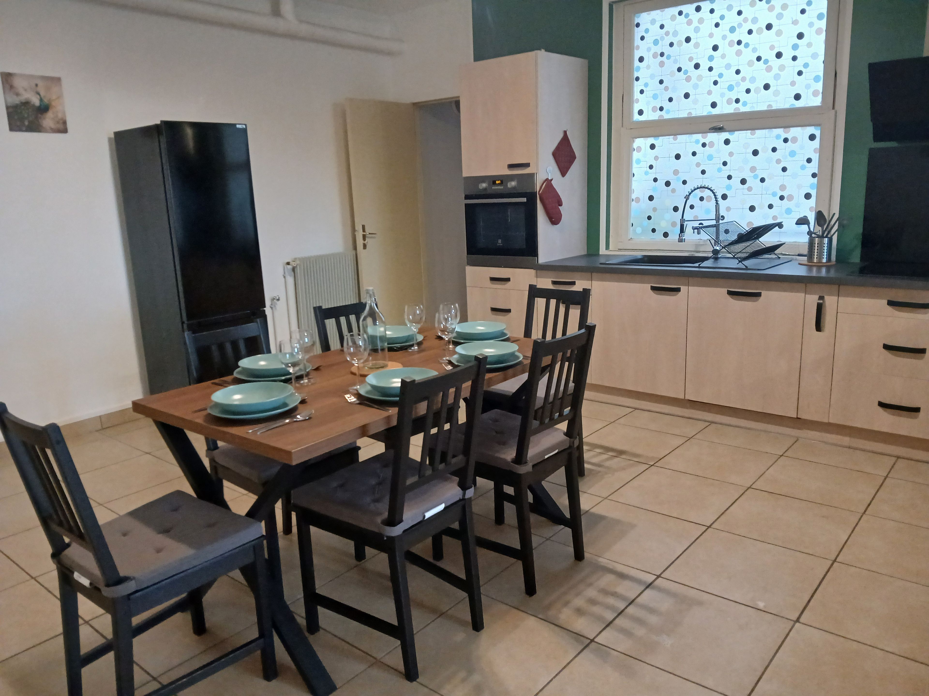 A dining area with a wooden table set for four, surrounded by chairs.