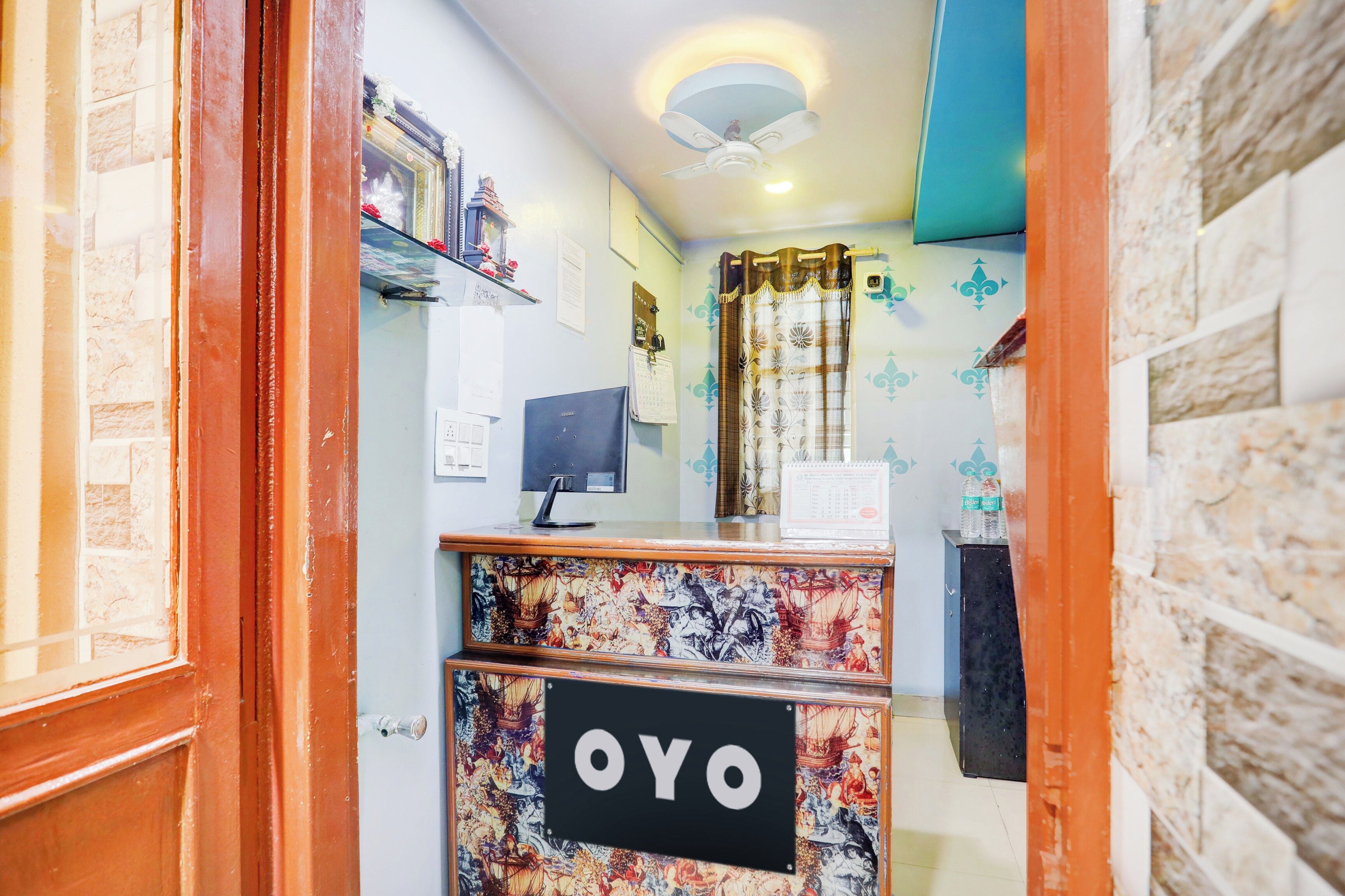Balcão de recepção com uma placa indicando 'OYO' e um monitor de computador.