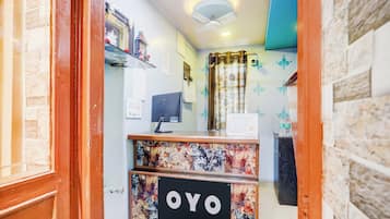 Balcão de recepção com uma placa indicando 'OYO' e um monitor de computador.