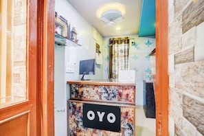Una mesa de recepción con un cartel que dice 'OYO' y un monitor de computadora.