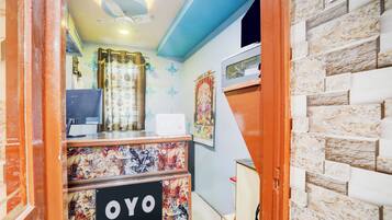 Un área de recepción con un cartel que dice 'OYO', un ventilador de techo, una cortina decorativa y una pared con un diseño estampado.