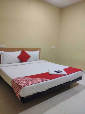 A single bed with a wooden headboard, white and red bedding, and a remote control on the bed. - Hotel O CANARIES RETIREES RESIDENCY (Vanur)