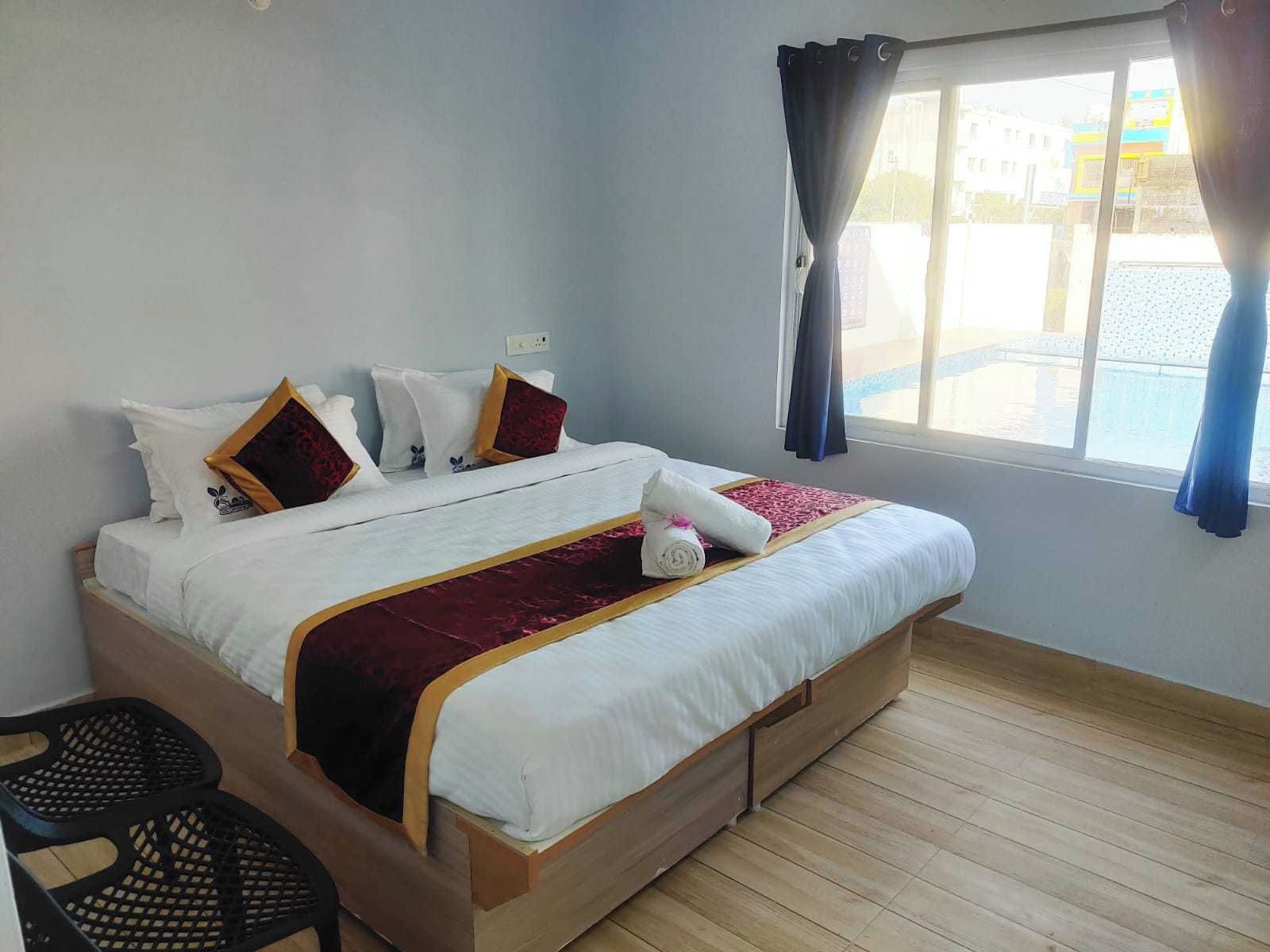 A neatly made bed with a white and red bedspread, a wooden headboard, and a window with curtains.