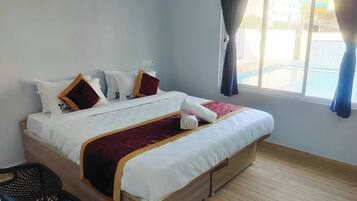 A neatly made bed with a white and red bedspread, a wooden headboard, and a window with curtains.