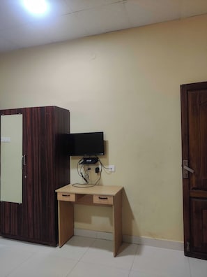 A room with a wooden wardrobe, a desk with a television, and a door. - Hotel O CANARIES RETIREES RESIDENCY (Vanur)