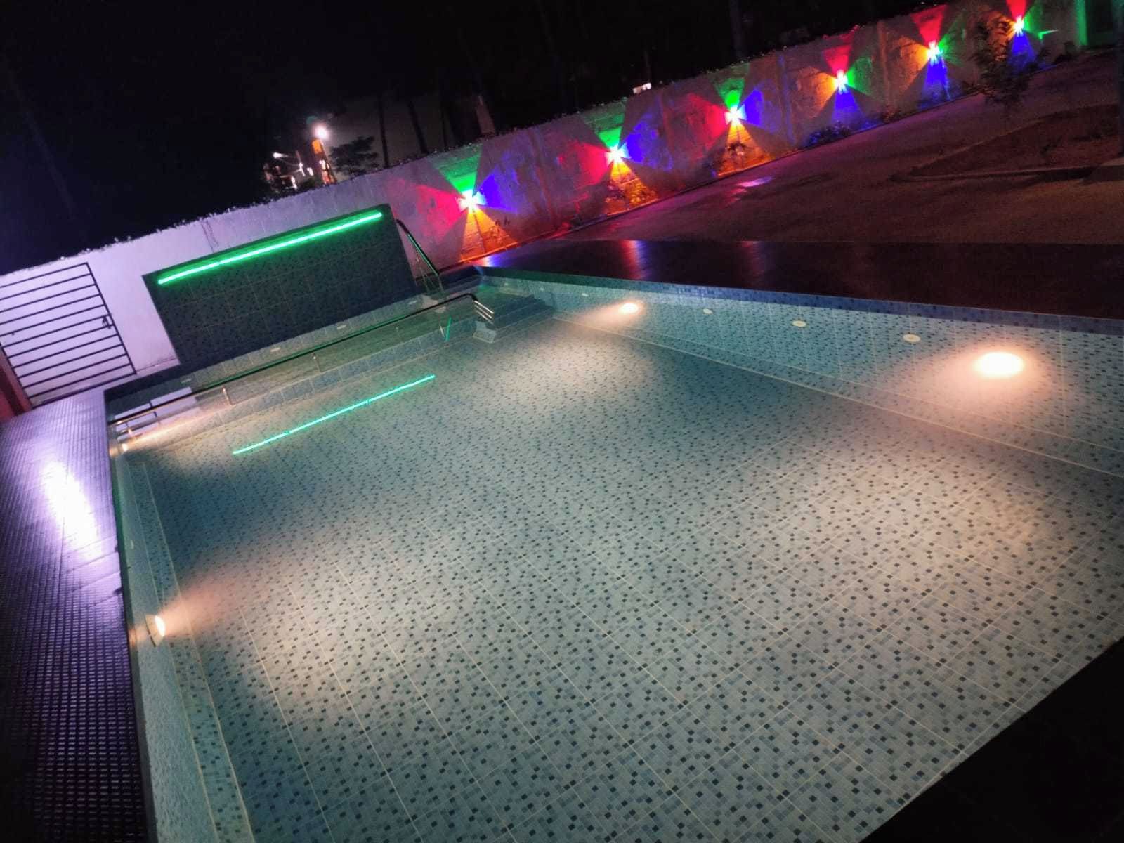 Una piscina al aire libre con suelo de baldosas y una pared baja.