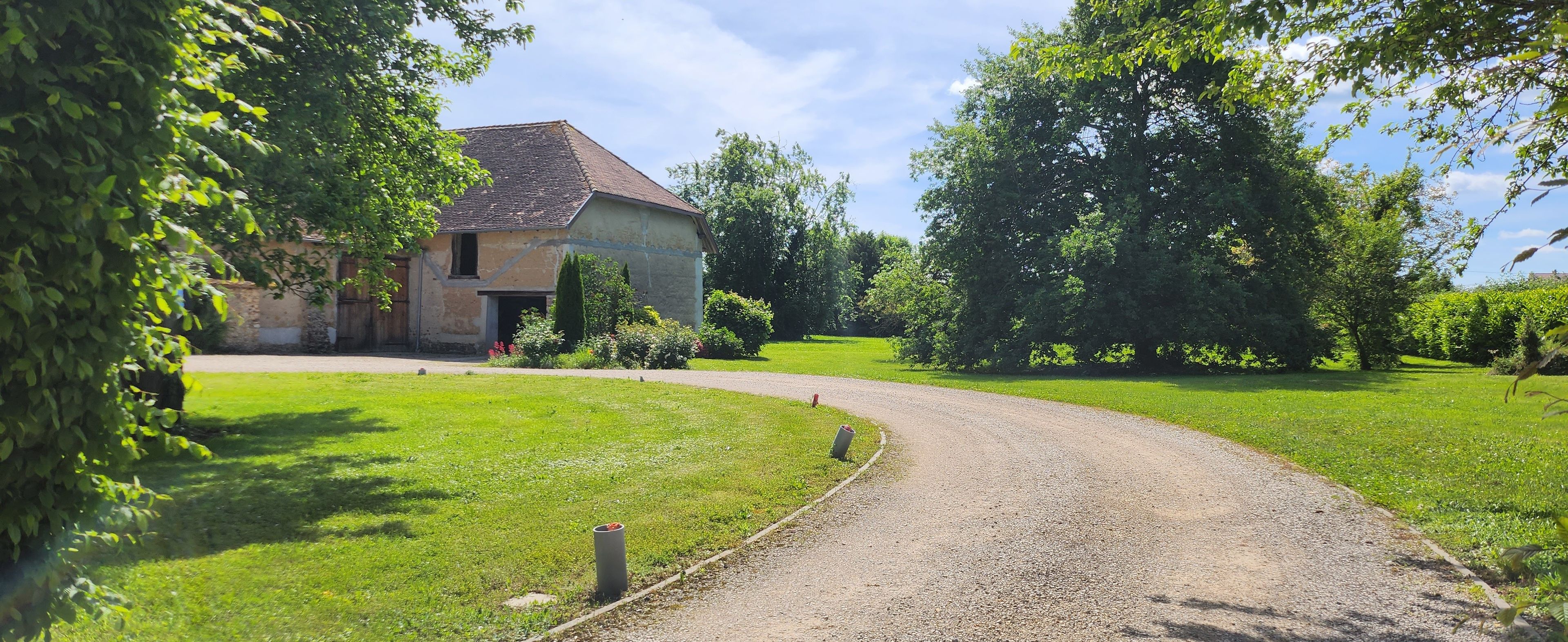 A rural road leading to a house with a sloped roof and a front door.