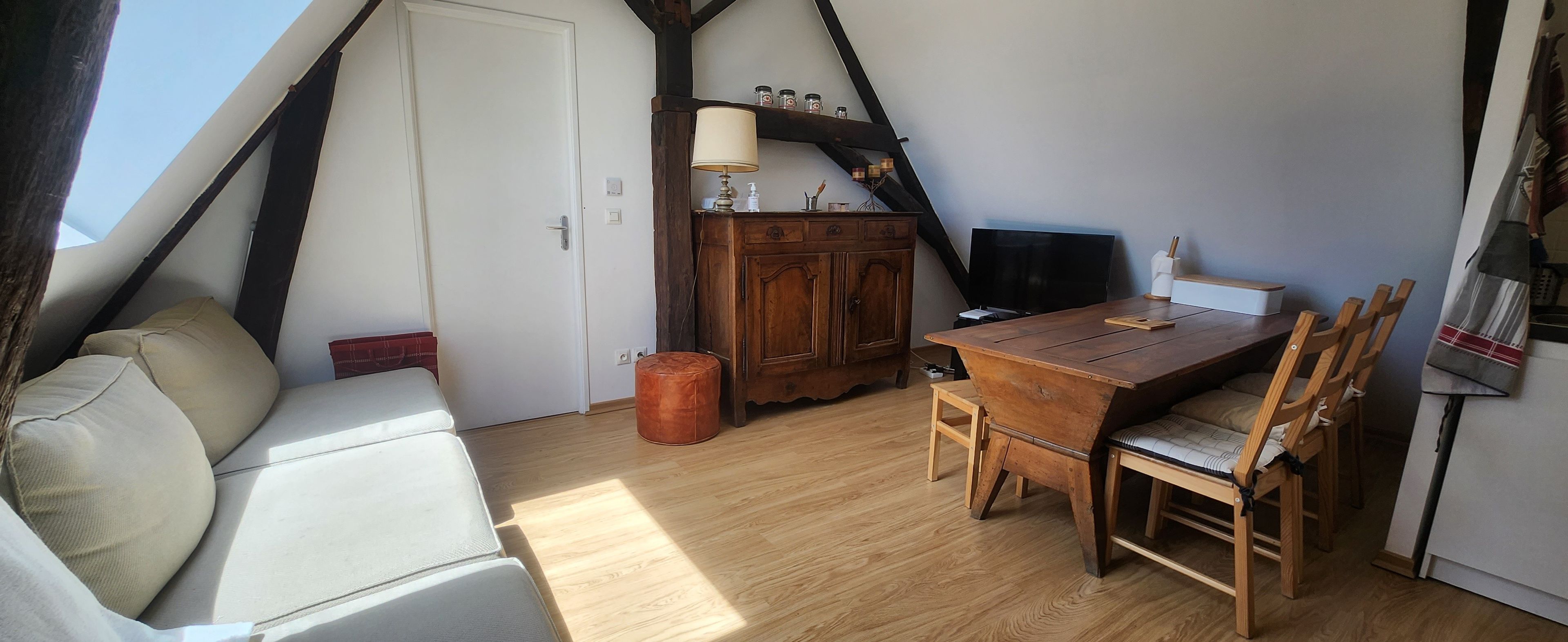 Una habitación acogedora con una mesa de comedor de madera, un sofá y una televisión.