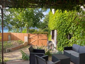 A covered outdoor seating area with wicker furniture, a barbecue grill, and a wooden fence. - House 'La Ferme Tchoukar' 10 Minutes' Walk from the Lake (Bilieu)