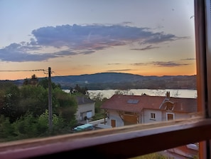 A view of a residential area with houses, a body of water, and hills in the background. - House 'La Ferme Tchoukar' 10 Minutes' Walk from the Lake (Bilieu)