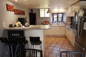 Eine moderne Küche mit einer zentralen Kochinsel, Barhocker, einem Kühlschrank und einem Schild mit der Aufschrift 'BON APPETIT'.