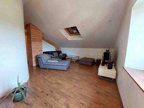 Ein Loft-Wohnraum mit schrägem Dach, einer Couch, einem kleinen Tisch und einer Heizung.