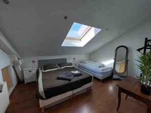 Ein Schlafzimmer mit einer Dachfenster, einem Bett, einem Nachttisch, einem Spiegel und einer Topfpflanze.