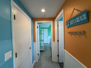Ein Flur mit Türen zu verschiedenen Zimmern, einer Leuchte an der Decke und einem an der Wand befestigten Schild.