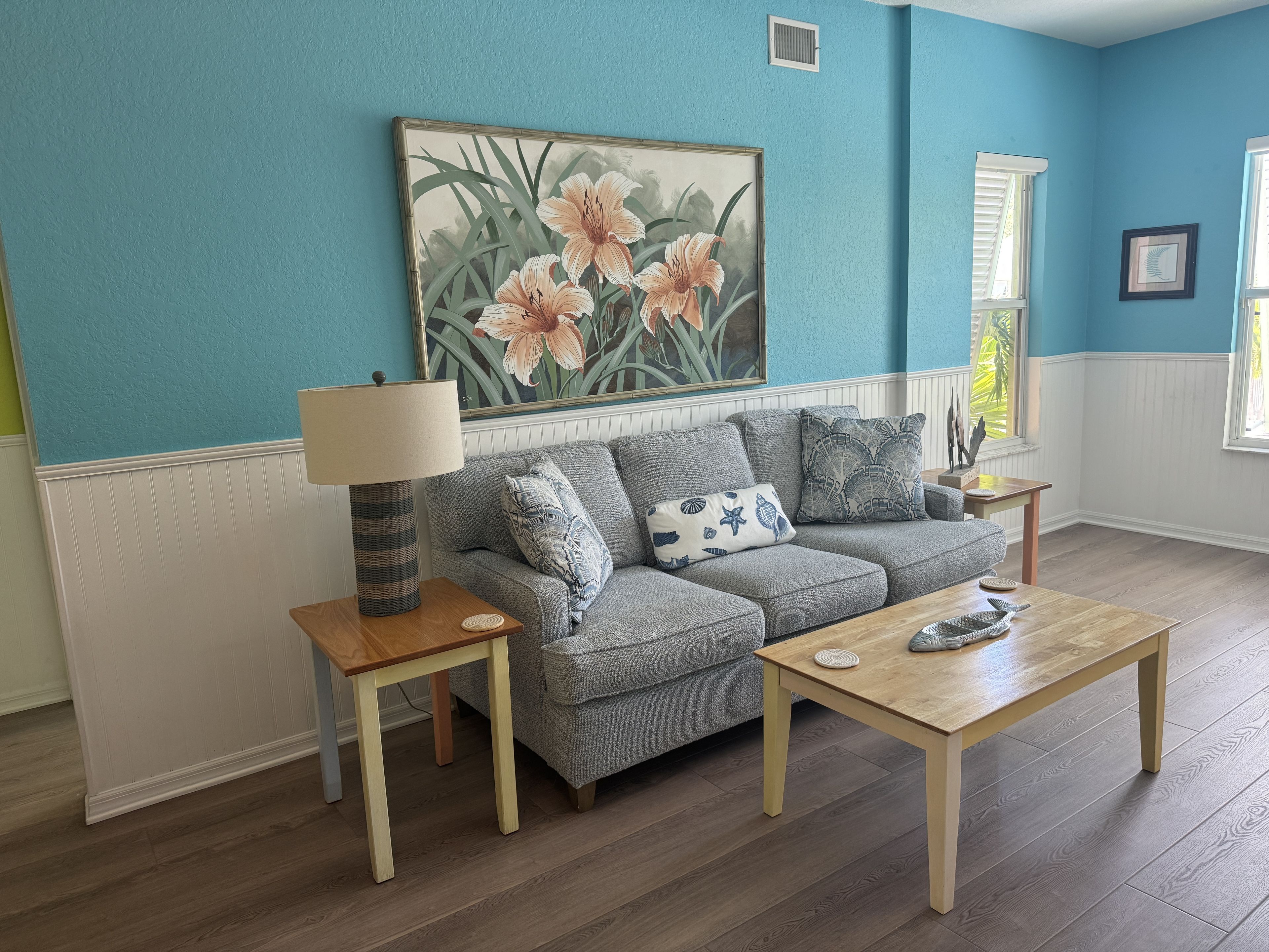 A living room with a grey sofa, a wooden coffee table, and a lamp on a side table.