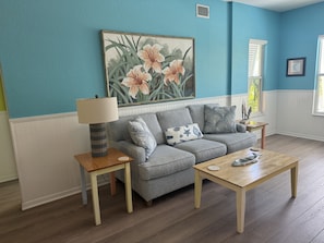 A living room with a grey sofa, a wooden coffee table, and a lamp on a side table. - Siesta Sunset Royale #2 2 Bedroom Apts (Siesta Key)