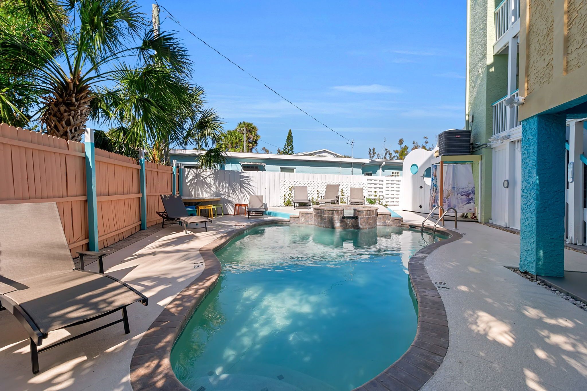 A swimming pool with lounge chairs and a wooden fence.