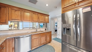 A modern kitchen with wooden cabinets, stainless steel appliances, and a built-in water dispenser. - Windward Bay Penthouse Escape 2 Bedroom Condo (Longboat Key)