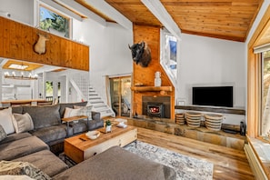 Ein geräumiger Wohnbereich mit Kamin, Fernseher und einer Couch.