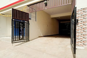 A gated entrance with a metal gate, a staircase leading to a balcony, and a tiled floor. - Hotel O Nature Comforts (Bangalore)
