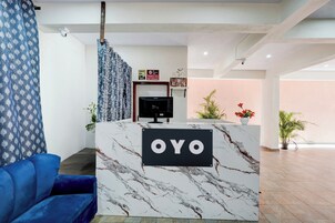 Balcão de recepção com bancada de mármore e placa indicando 'OYO'.