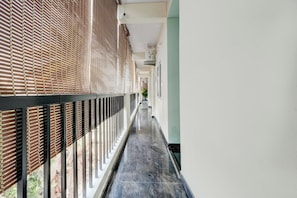 A corridor with a patterned wall, a black railing, and a marble floor. - Hotel O Nature Comforts (Bangalore)
