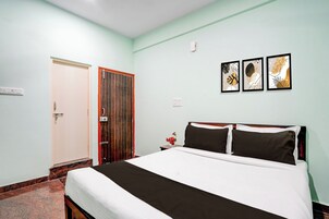 Quarto com cama, porta e três obras de arte emolduradas na parede.