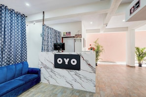 A reception area with a marble counter, a blue sofa, and a 'NO SMOKING' sign. - Hotel O Nature Comforts (Bangalore)