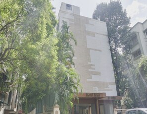 Un bâtiment d’hôtel doté d’une façade moderne, d’une entrée bien visible et entouré de verdure.