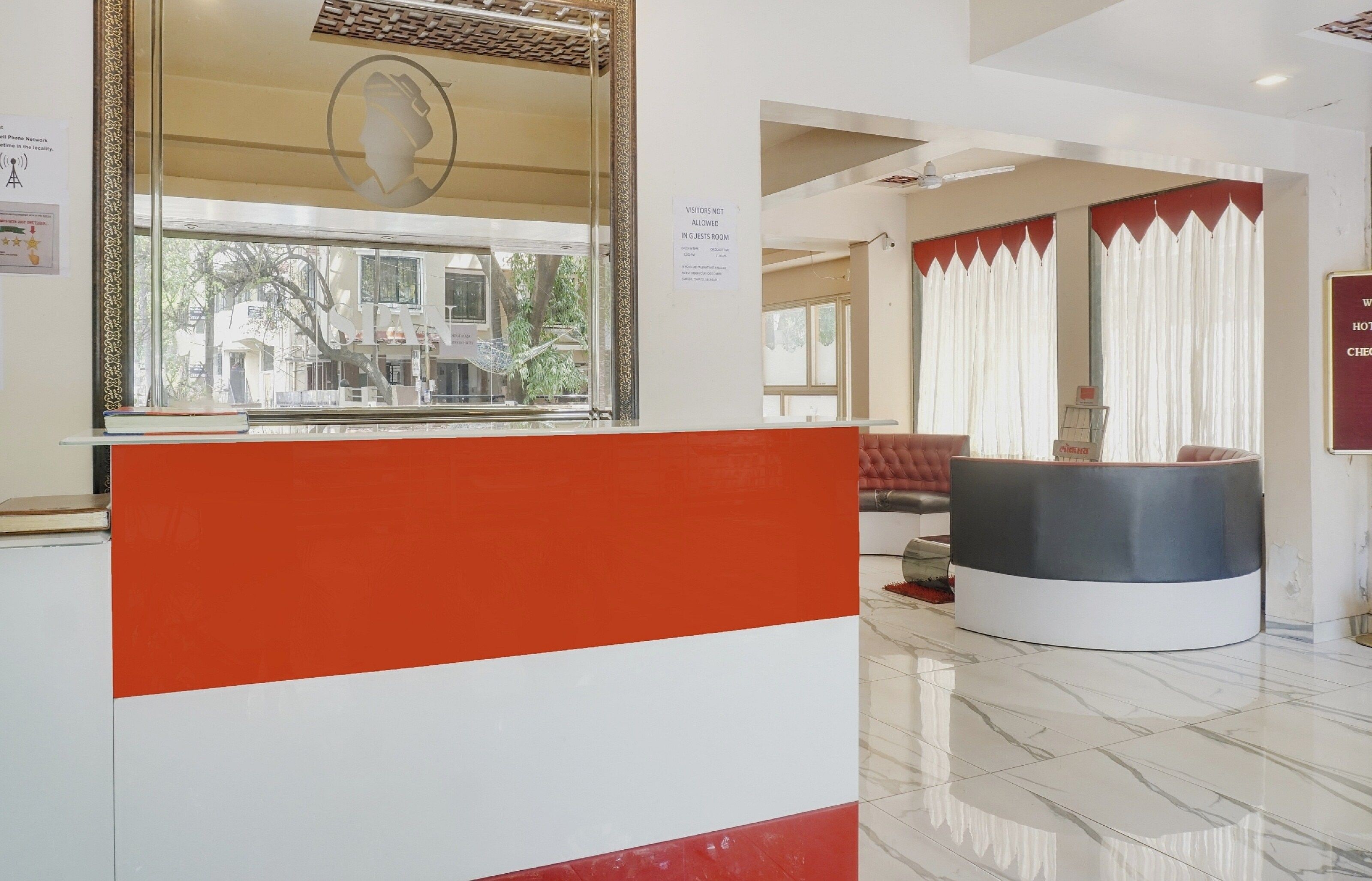 A reception area with a counter, a seating area with a sofa and armchairs, and a view of the outside through a window.