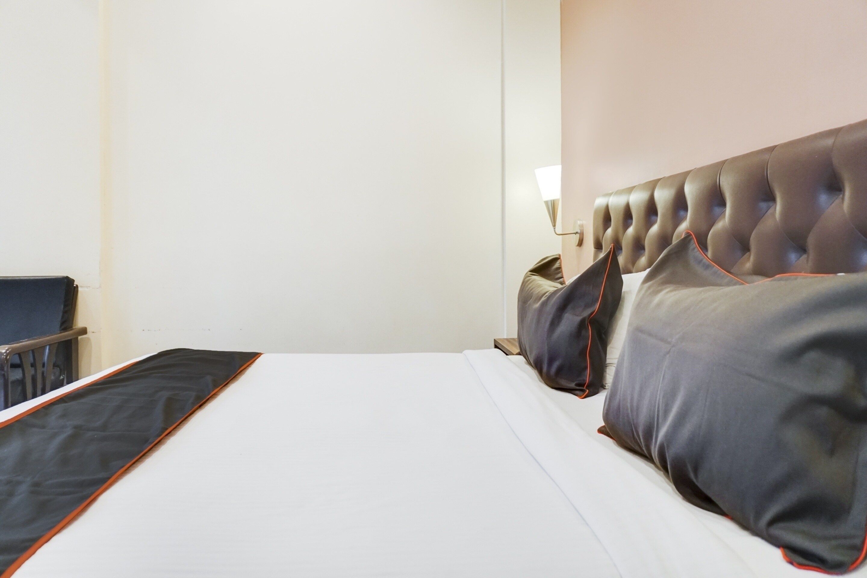 Ett hotellrum med en säng, en stol och en vägglampa.