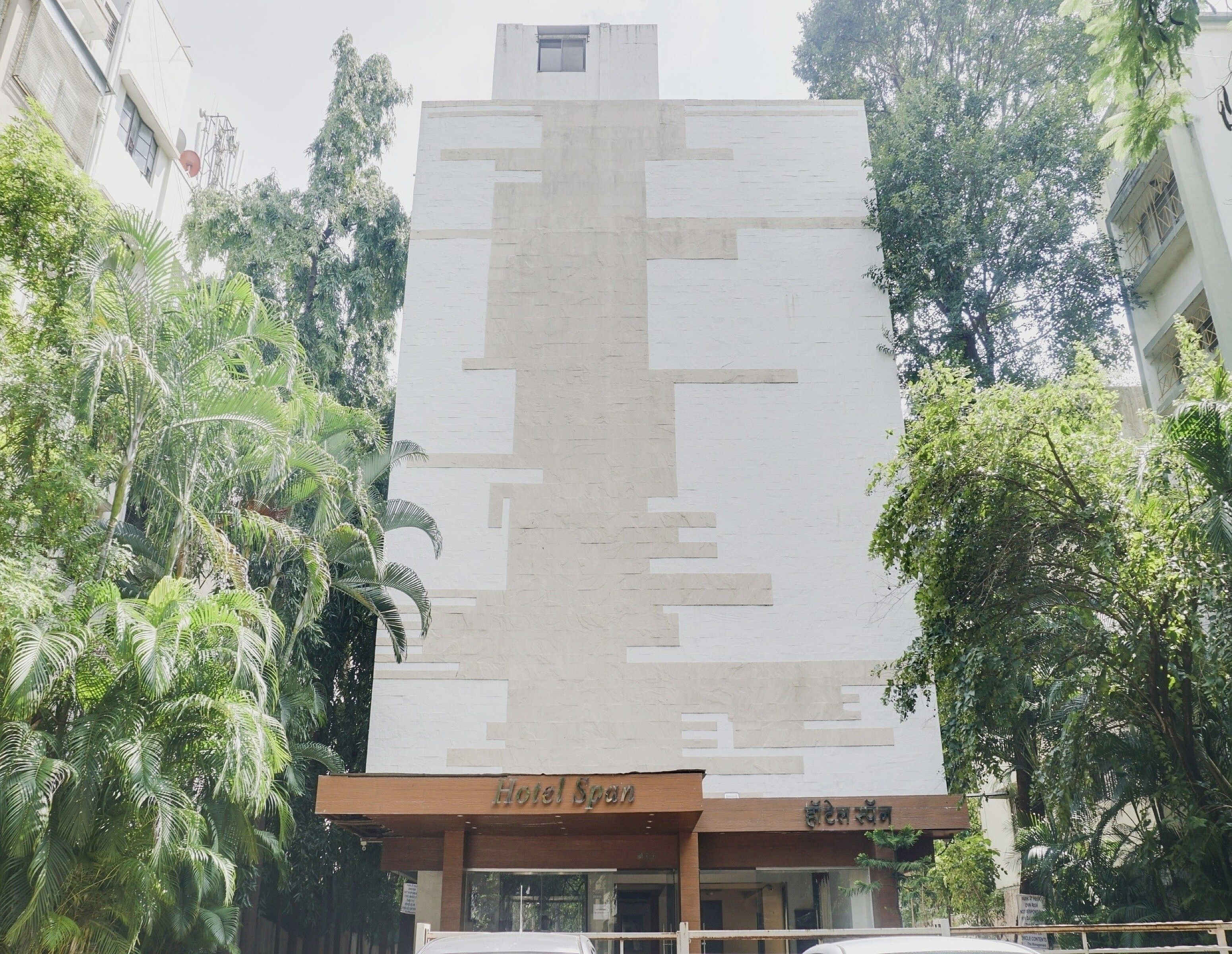 Un hôtel doté d’une façade moderne, d’une enseigne indiquant le nom de l’hôtel et entouré d’arbres.