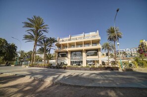 Un edificio de varios pisos con un llamativo letrero que dice 'SEA VIEW', rodeado de palmeras.