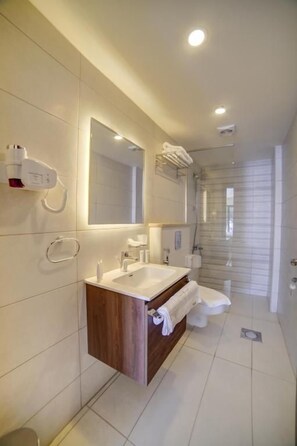 Un baño moderno con tocador, espejo, toallero y zona de ducha.
