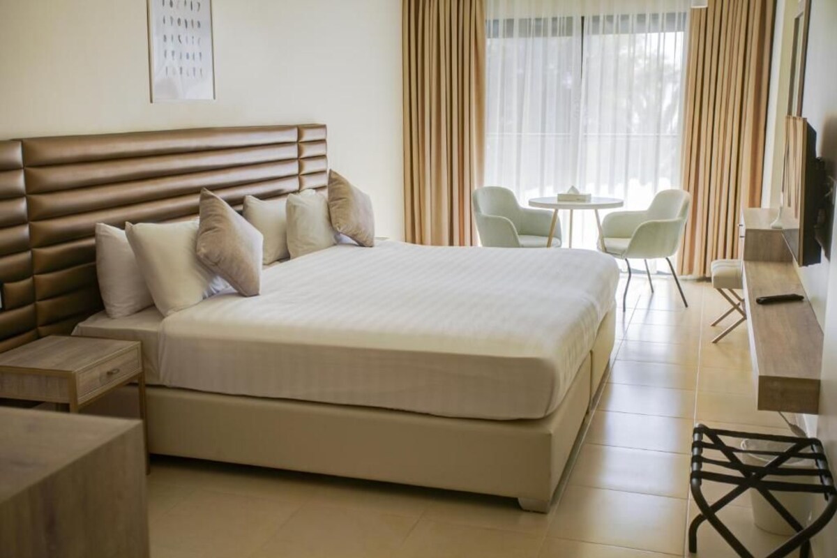 Una habitación de hotel con una cama grande, una mesita de noche, un escritorio, una silla y un televisor.